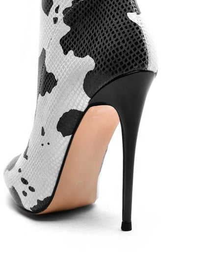 Bottines femme à talons aiguilles avec imprimé vache blanc. Fermeture éclair latérale, bout pointu. Disponibles en grandes tailles.