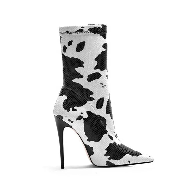 Bottines femme à talons aiguilles avec imprimé vache blanc. Fermeture éclair latérale, bout pointu. Disponibles en grandes tailles.